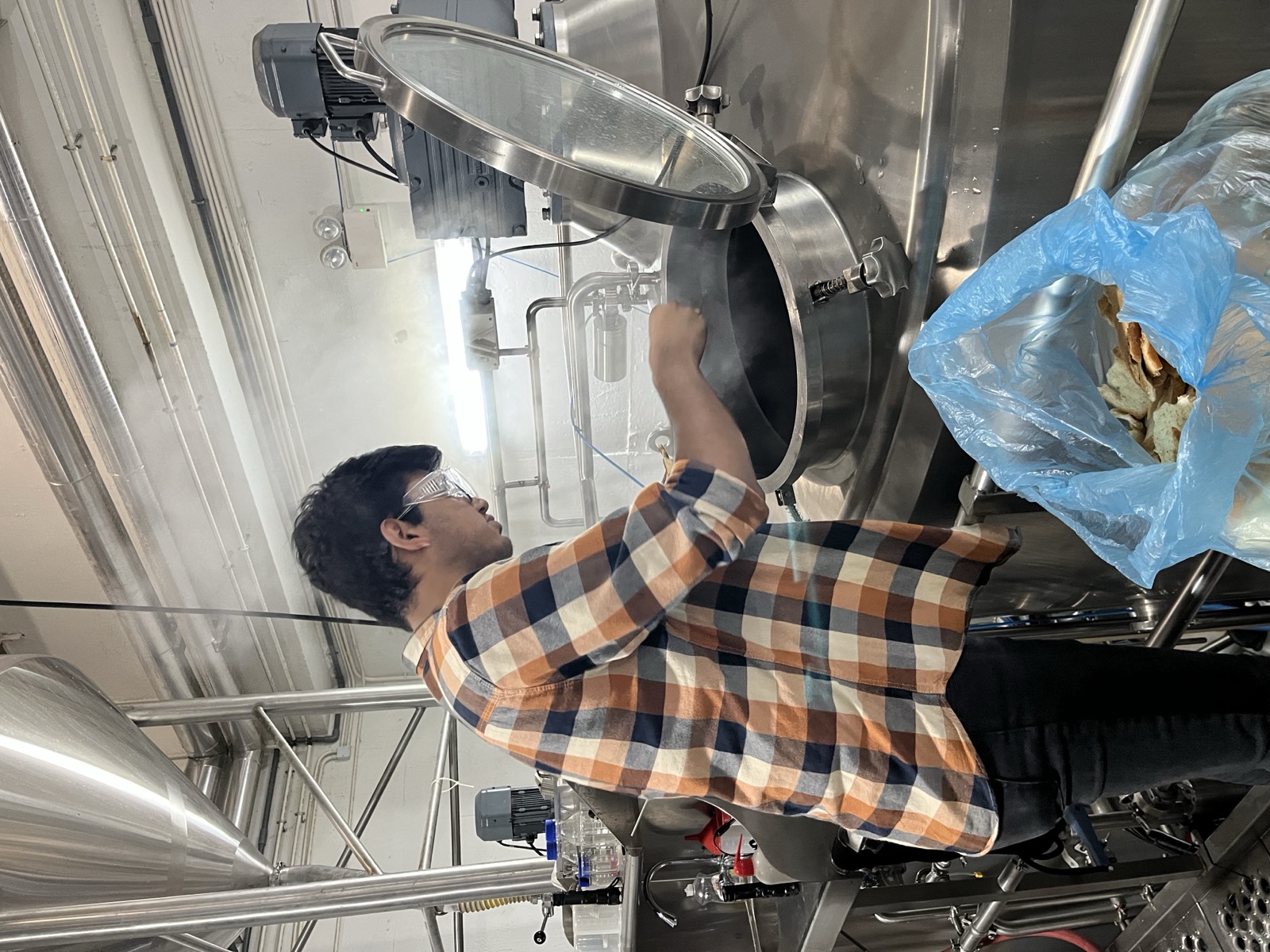 Naman Tekriwal loading surplus bread into a mash tun at the brewery